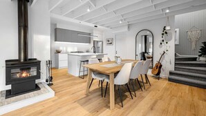 A modern living space with a fireplace, dining area, kitchen, and staircase. - Njordland -Stunning Oceanside Scandi renovation (Rye)