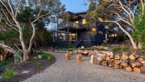 A modern house with a two-story deck, surrounded by trees and a gravel path. - Njordland -Stunning Oceanside Scandi renovation (Rye)