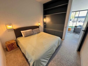A bedroom with a bed, bedside tables, a built-in bench, and a view of the outdoors. - Quay-Walk to beach Gas Heated Pool, Spa Trampoline (Blairgowrie)