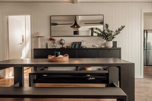 A modern kitchen with a dark wooden table, a built-in bench, and a mirrored backsplash. - Quay-Walk to beach Gas Heated Pool, Spa Trampoline (Blairgowrie)