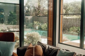 A room with a large window overlooking a backyard with a pool and garden. - Quay-Walk to beach Gas Heated Pool, Spa Trampoline (Blairgowrie)