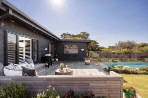 A modern house with a deck, outdoor seating, and a swimming pool. - Quay-Walk to beach Gas Heated Pool, Spa Trampoline (Blairgowrie)