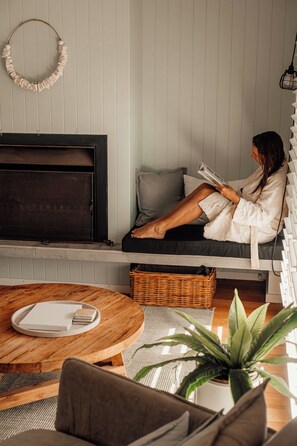 A cozy living room with a sofa, a coffee table, and a fireplace. - Quay-Walk to beach Gas Heated Pool, Spa Trampoline (Blairgowrie)