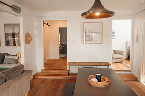 Un intérieur moderne avec un plancher en bois, une table à manger agrémentée d’un panier tressé et une suspension décorative.