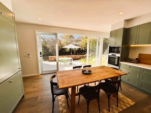 A modern kitchen with a wooden dining table, chairs, and a sliding glass door leading to an outdoor patio. - Safe Haven -walk to beach/shops, full renovation (Sorrento)