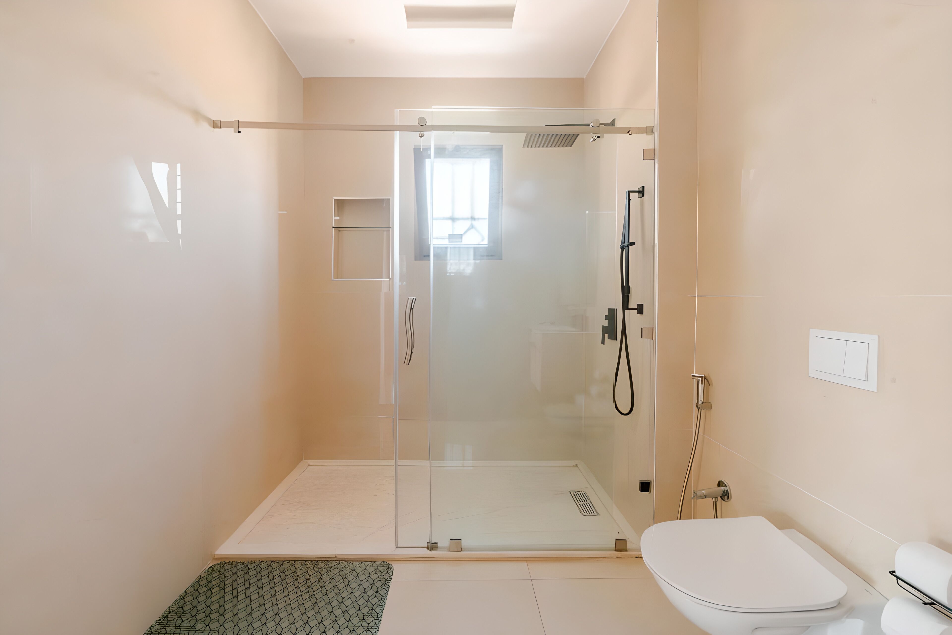 Een moderne badkamer met een douche met glazen wand, een wit toilet en een klein raam.