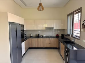 Eine moderne Küche mit Kühlschrank, Herd, Spüle und Holzschränken.