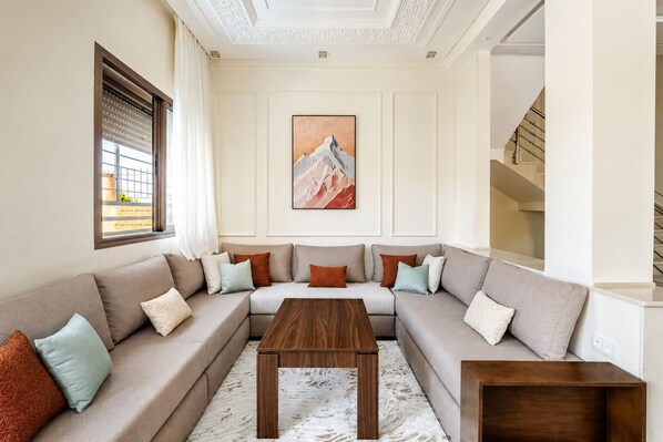 Ein Wohnzimmer mit einem Ecksofa, einem Holztisch und einem Bild an der Wand.