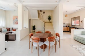 A modern living space with a dining area, a staircase, and a kitchen.