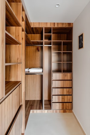 Ein begehbarer Kleiderschrank mit Holzböden und Schubladen, einer weißen Decke und einem gerahmten Bild an der Wand.
