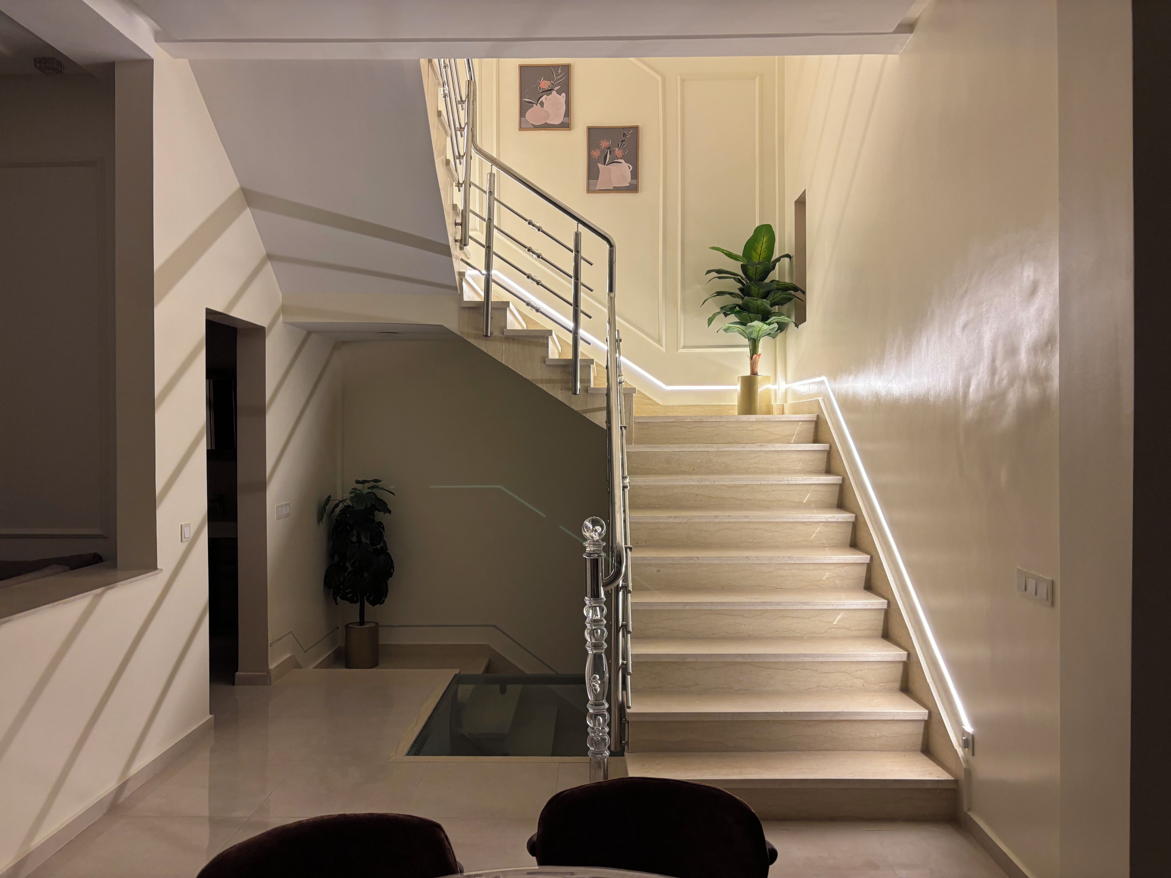 Eine Treppe mit einem Glastisch als Podest und einer Topfpflanze.