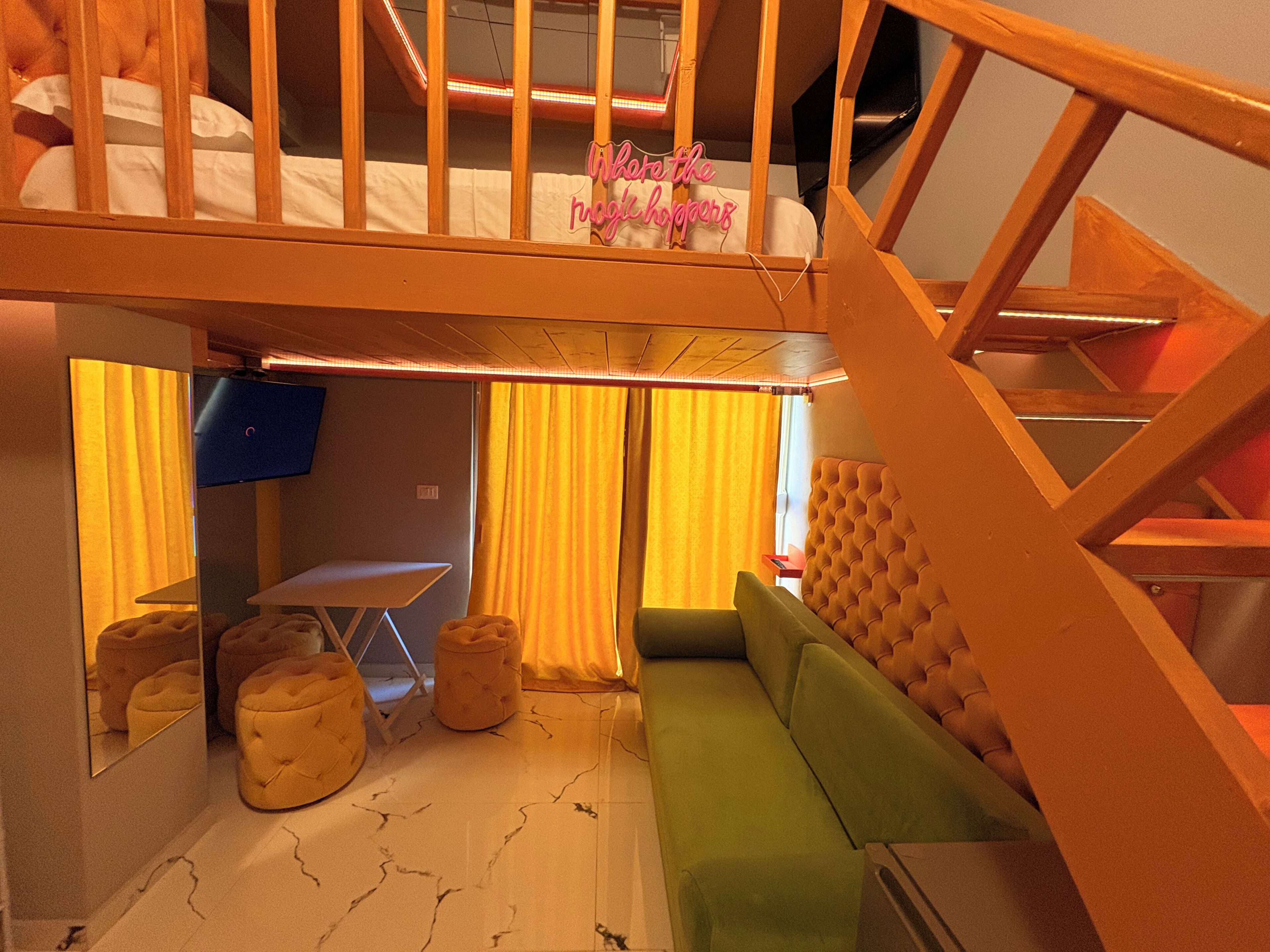 Una habitación con una cama nido, un sofá verde, una pequeña mesa y una silla.