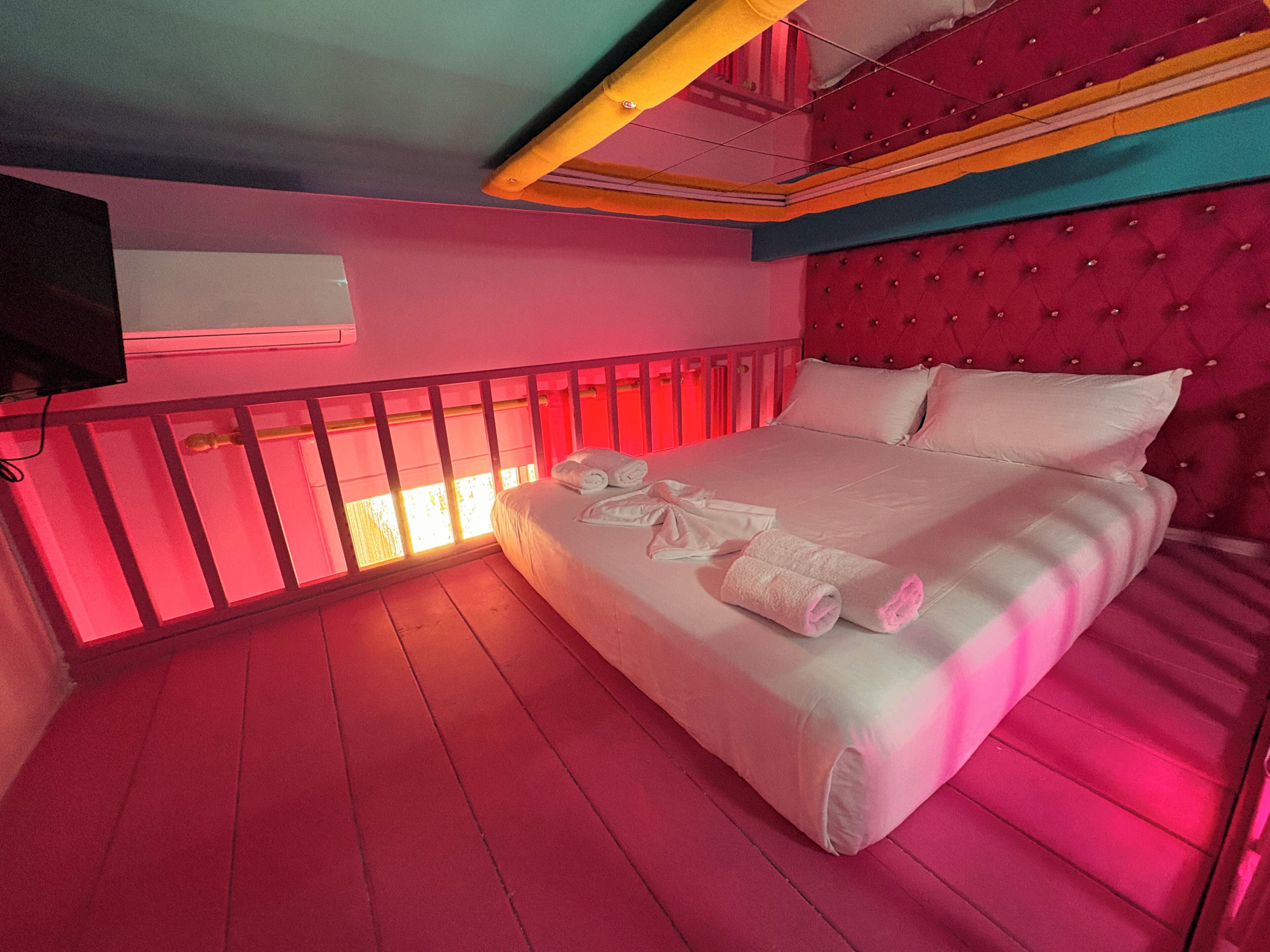 Une chambre avec un lit, un téléviseur fixé au mur et un balcon doté d’une balustrade.