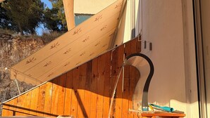 A hot tub with water flowing, a wooden deck, and a white wall. - Romance Apartment (Sarande)