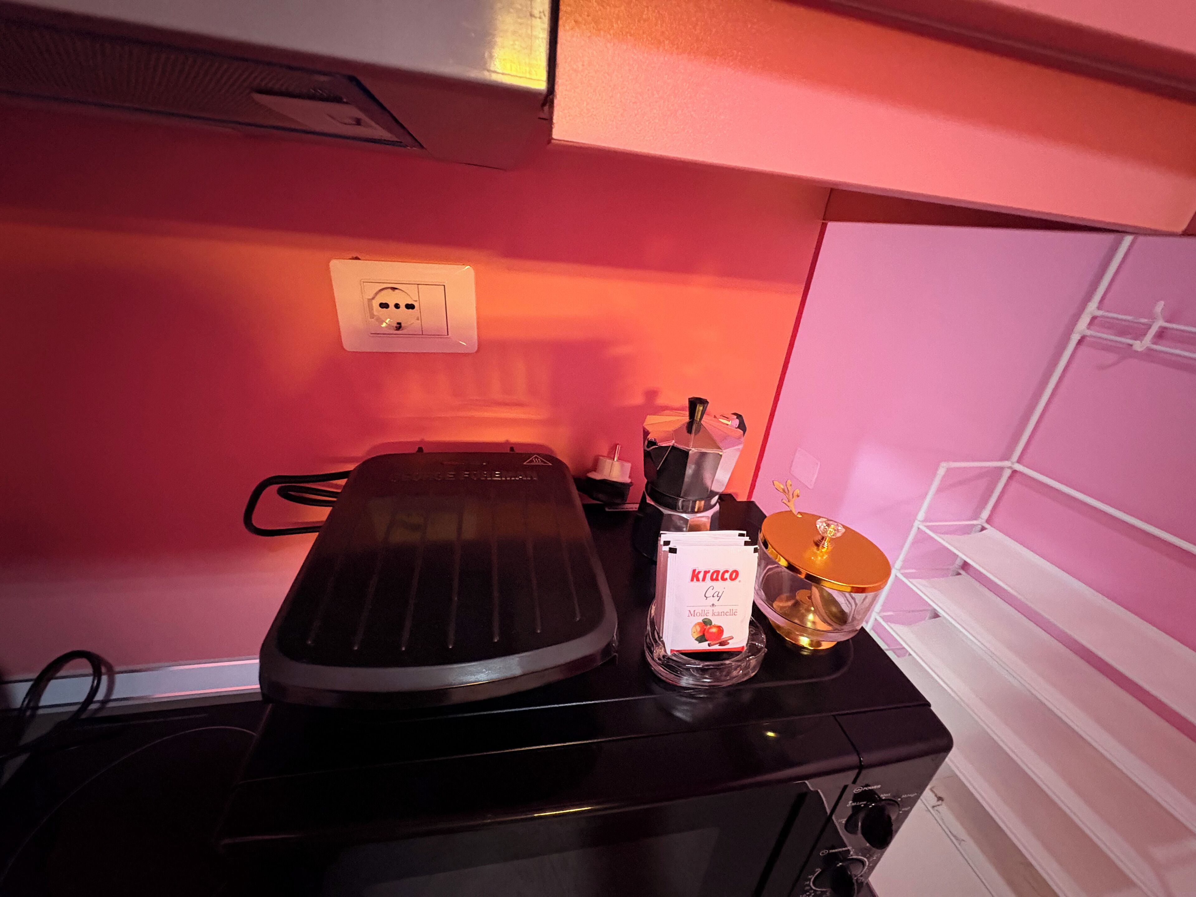 Una cocina con estufa eléctrica portátil, una cafetera y un paquete de café Kraco Caju.