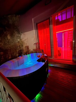 A hot tub with two glasses of wine, a wooden deck, and a red-lit room. - Romance Apartment (Sarande)
