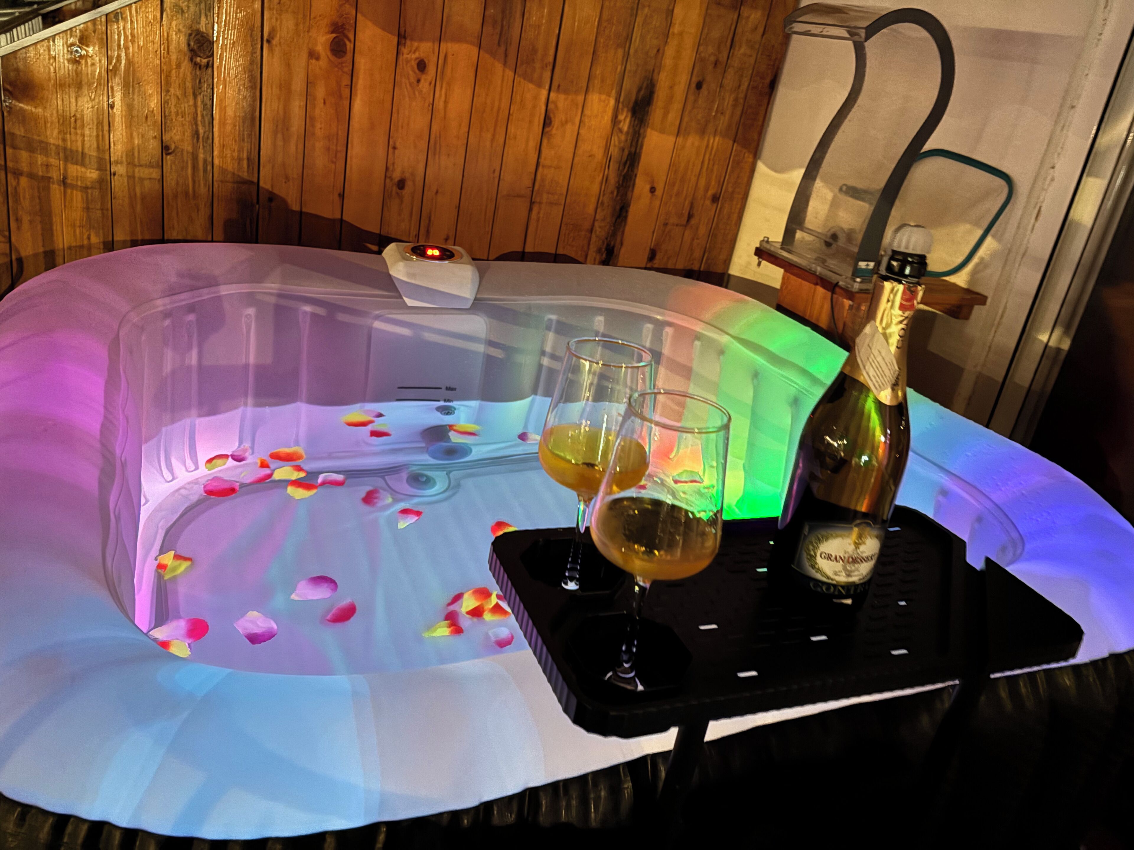 Hidromasaje con pétalos de rosa, dos copas de vino y una botella de champán.