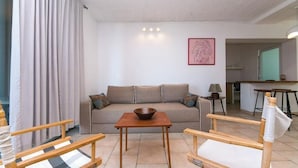Een woonkamer met een bank, een houten salontafel en twee houten stoelen.