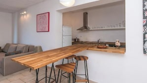 Een moderne keuken met een houten aanrecht, barstoelen en een hangende lamp.
