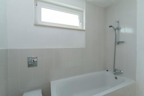 Un baño con bañera, ventana y ducha.