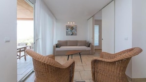 Un salon moderne avec un canapé, deux fauteuils en osier et une table basse.
