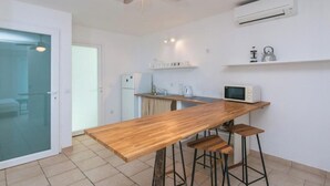 Une cuisine moderne avec un comptoir-bar en bois, des tabourets, un ventilateur de plafond et un appareil de climatisation.