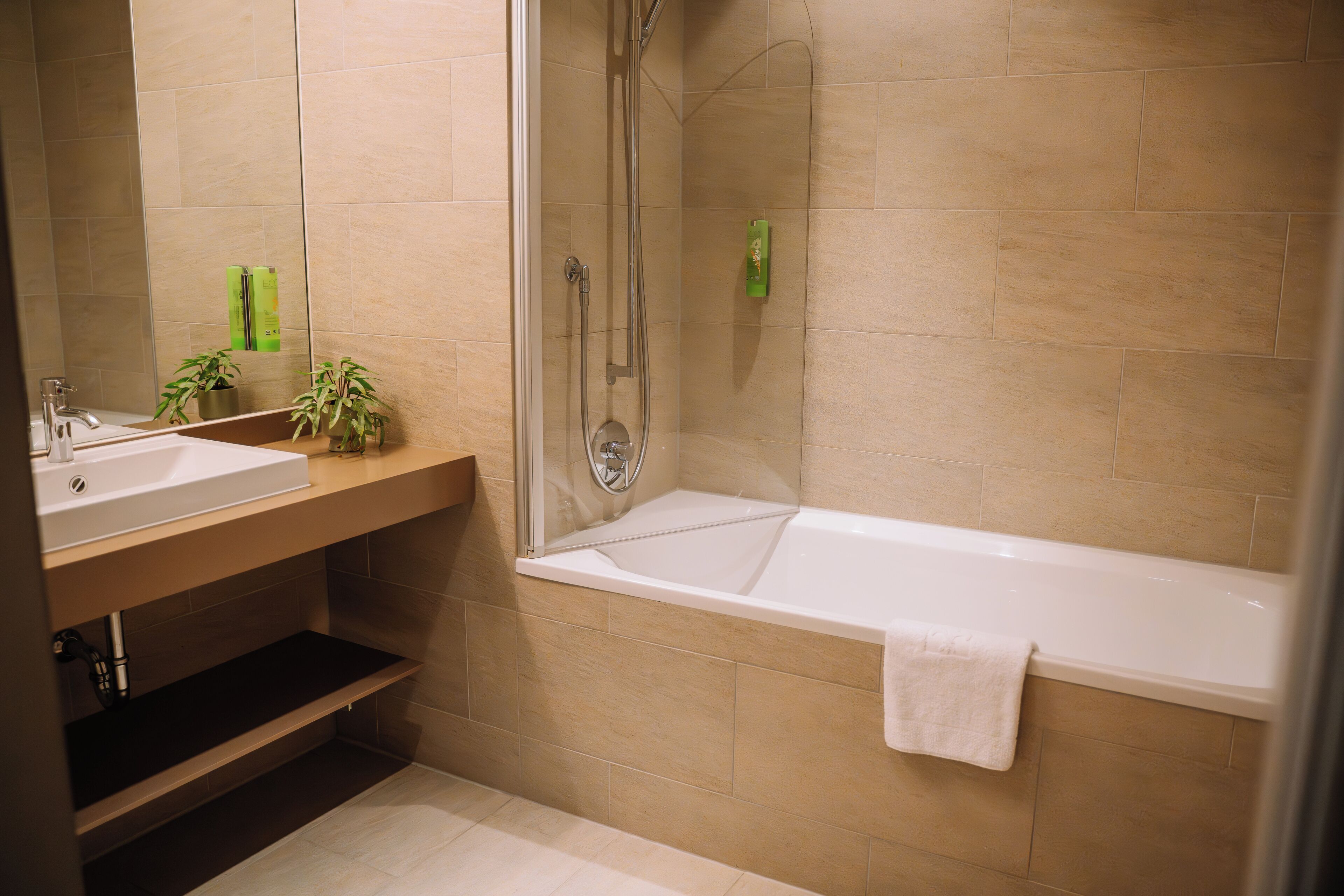 A modern bathroom with a glass-enclosed shower, a white bathtub, and a vanity with a mirror.