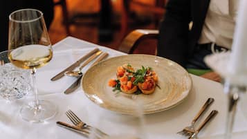 Une table à manger avec une assiette de nourriture, des couverts et un verre de vin blanc.