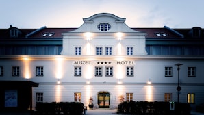 Un bâtiment blanc avec l’enseigne « AUSZEIT HOTEL » et trois étoiles au-dessus de l’entrée.
