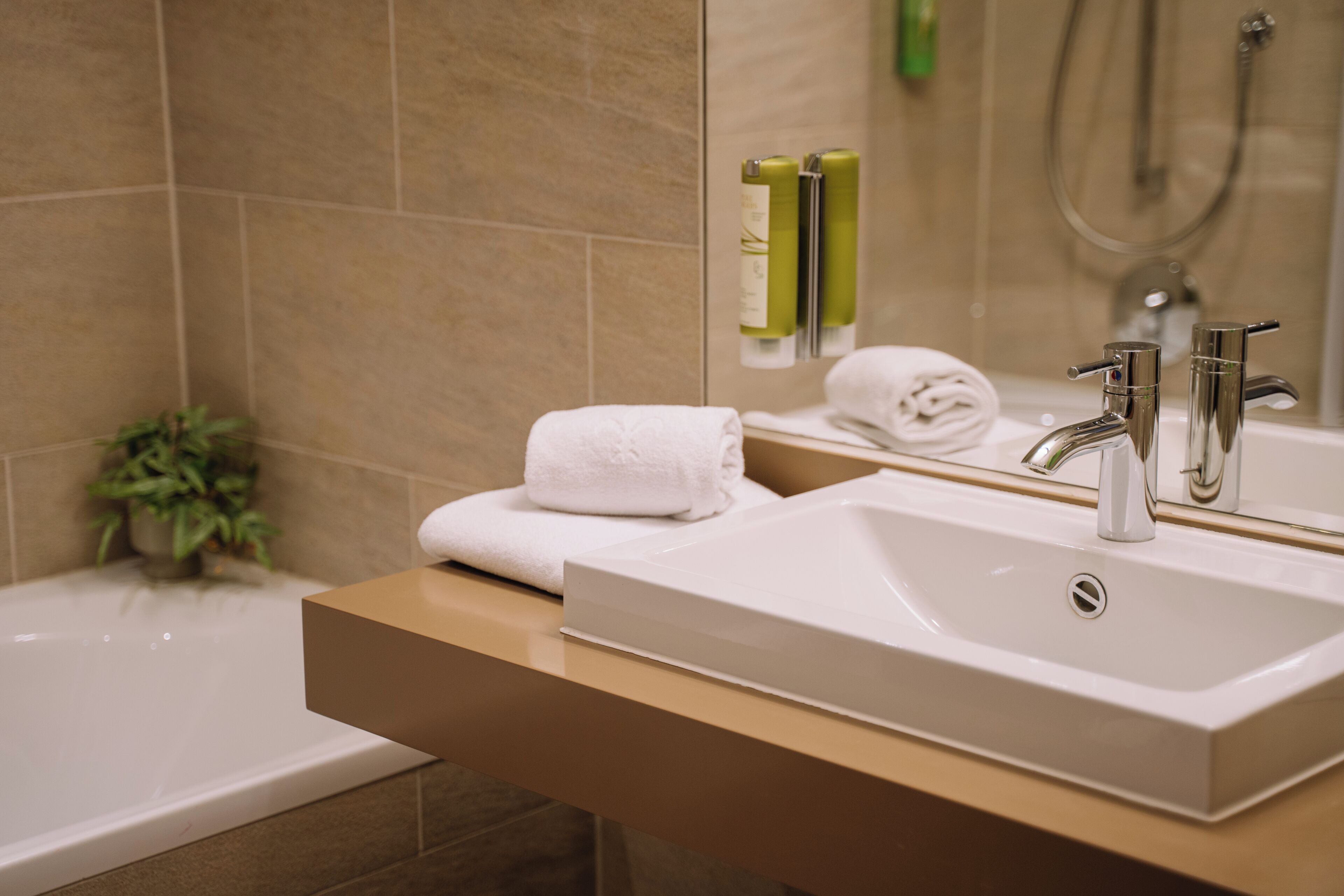 Un baño moderno con un lavabo blanco, un espejo y una zona de ducha.