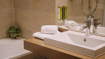 Un baño moderno con un lavabo blanco, un espejo y una zona de ducha.