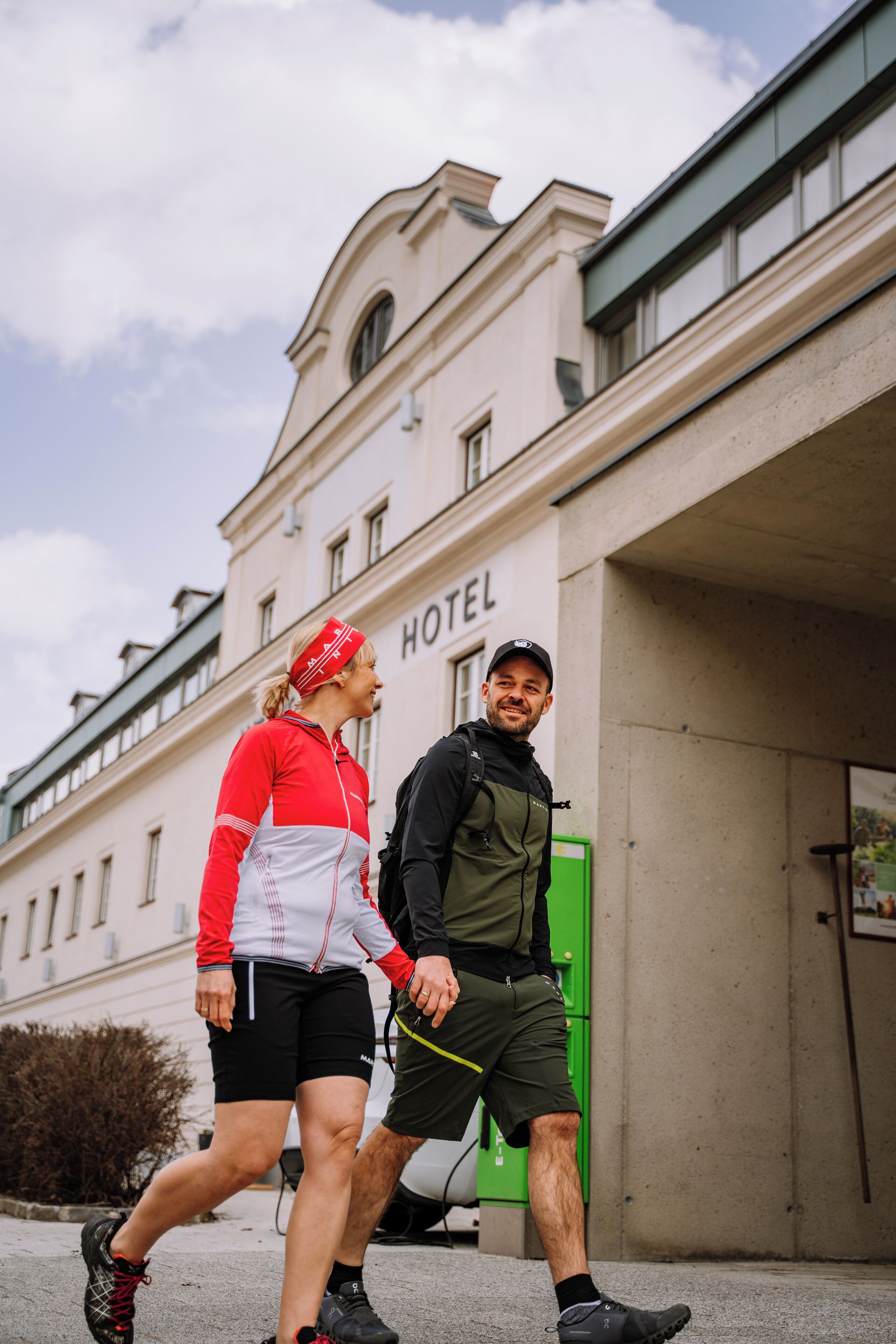 Two people walking in front of a building labeled "HOTEL".