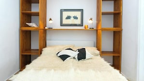 A bedroom with a bed, a wooden headboard, a framed picture, and two bedside lamps. - Villa IVKA Apartment D - terrace with panoramic views, 1 BR + ensuite bathroom (Brela)