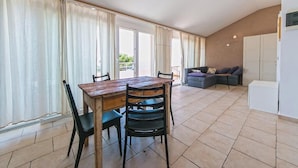 A spacious living area with a wooden dining table, black chairs, a grey sofa, and a white cabinet. - Villa IVKA Apartment D - terrace with panoramic views, 1 BR + ensuite bathroom (Brela)
