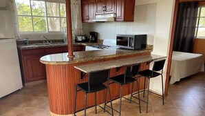 A kitchen with a granite countertop, wooden cabinets, a microwave, and a gas stove. - 2nd Visit Guaranteed (Sosúa)