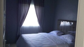 A bedroom with a bed, curtains, and a window. - Pintu Waluh Homestay (Takengon)