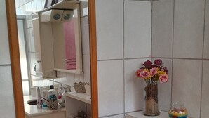 A bathroom with a mirror, shelves, a sink, and a toilet. - Joinville has Casa Vintage - comfort and a privileged location. (Joinville)