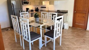 Eine kompakte Küche mit Esstisch, Stühlen, Kühlschrank, Mikrowelle, Herd und Schränken.