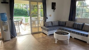 A living room with a sofa, a round coffee table, and a water dispenser. - Villa Belle Amour (Sosúa)