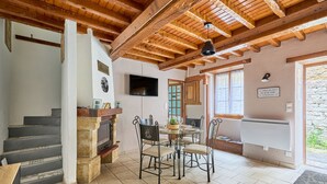 Un comedor con una mesa redonda y sillas, una chimenea y una escalera.
