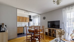Una cocina moderna con armarios de madera, una mesa de comedor con sillas, un televisor y una cafetera.