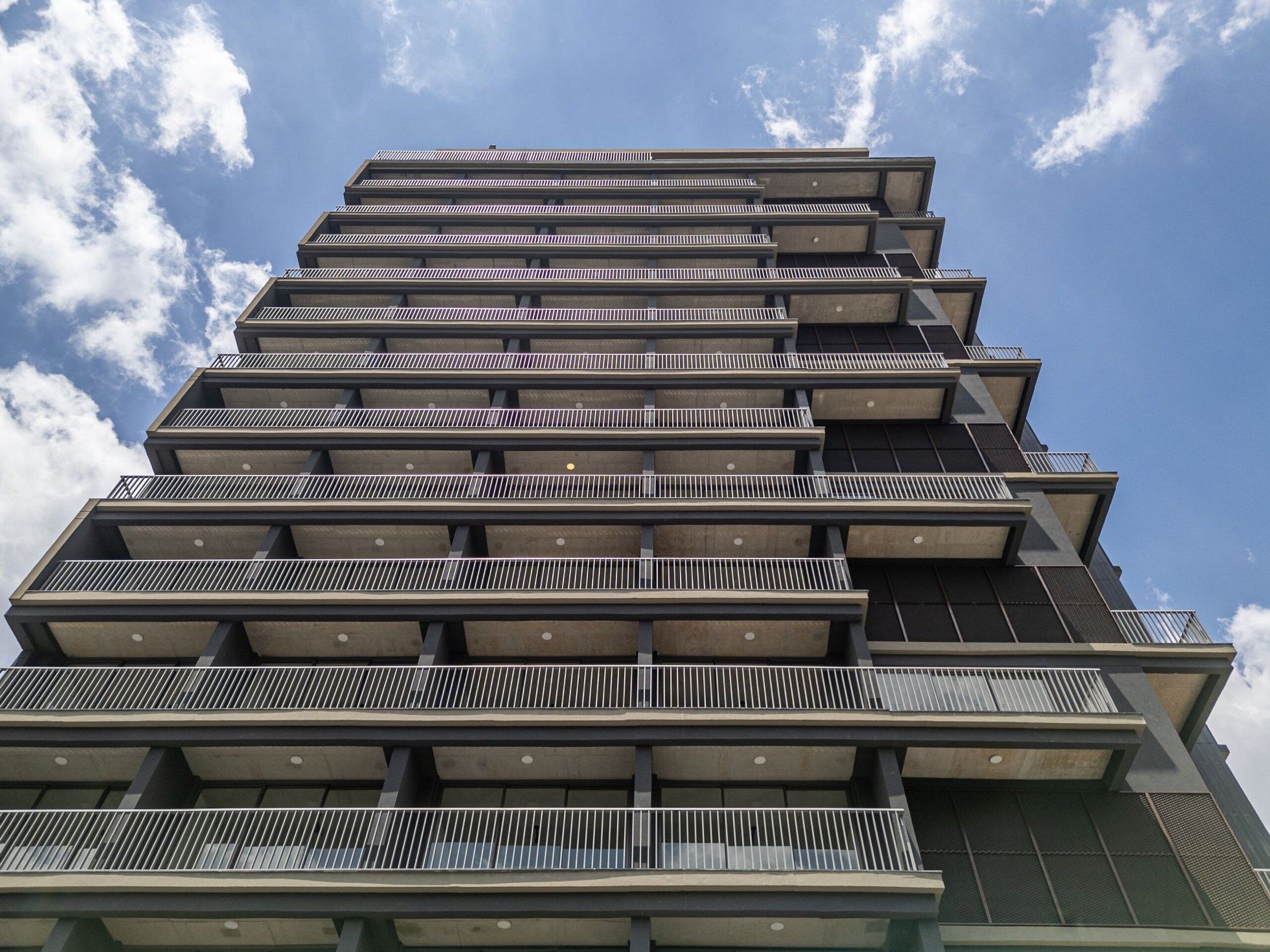 Un edificio de varios pisos con balcones y un cielo despejado al fondo.