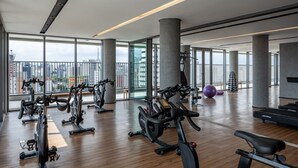 A spacious gym with multiple exercise bikes and a large window offering a city view.