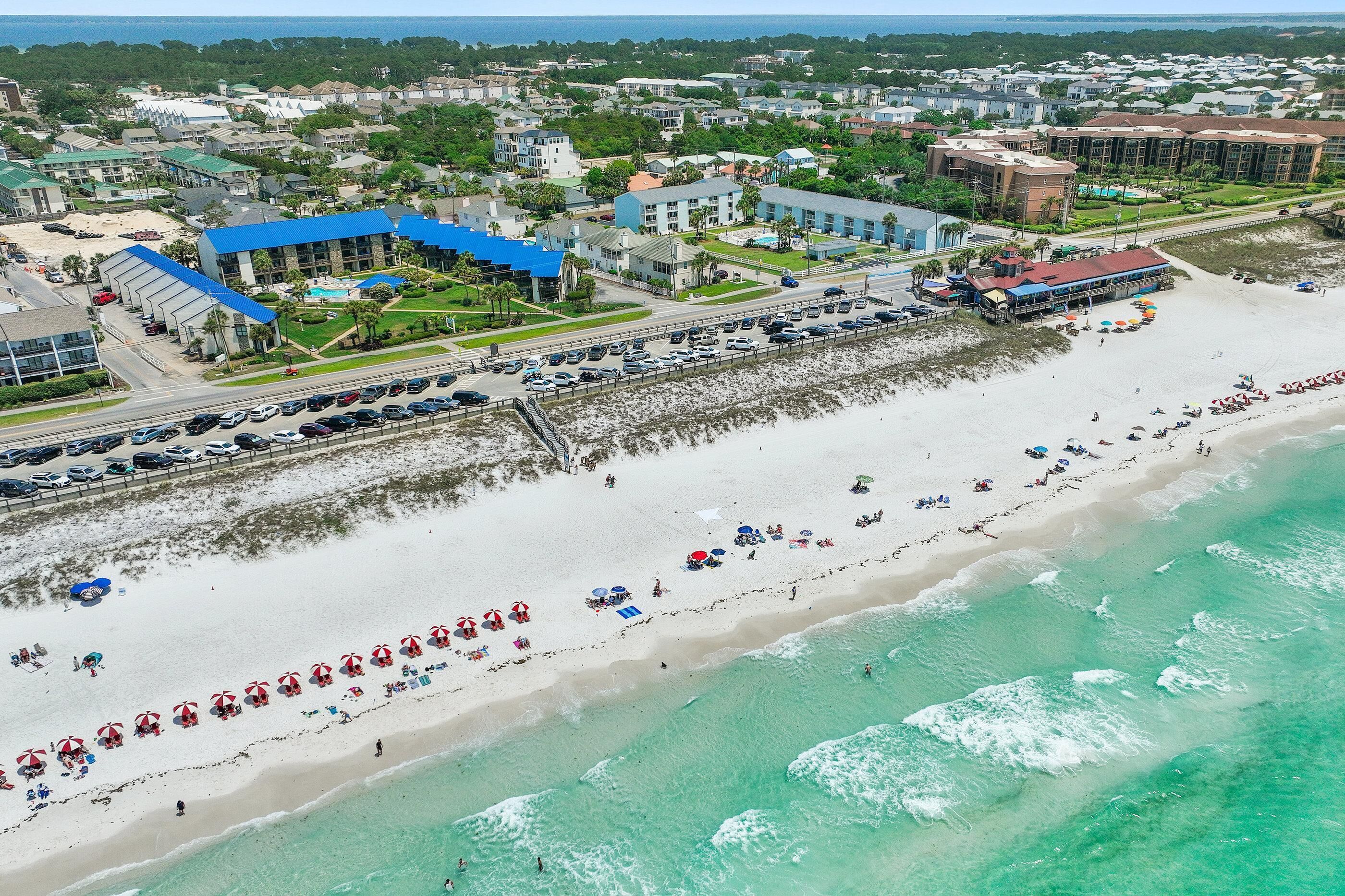 A coastal hotel with a beach view, multiple swimming pools, and a parking area.