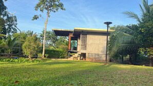 A modern building with a flat roof and large windows, surrounded by a well-maintained lawn and various trees. - ที่พัก ใกล้เมืองสุราษฎร์ธานี (Surat Thani)