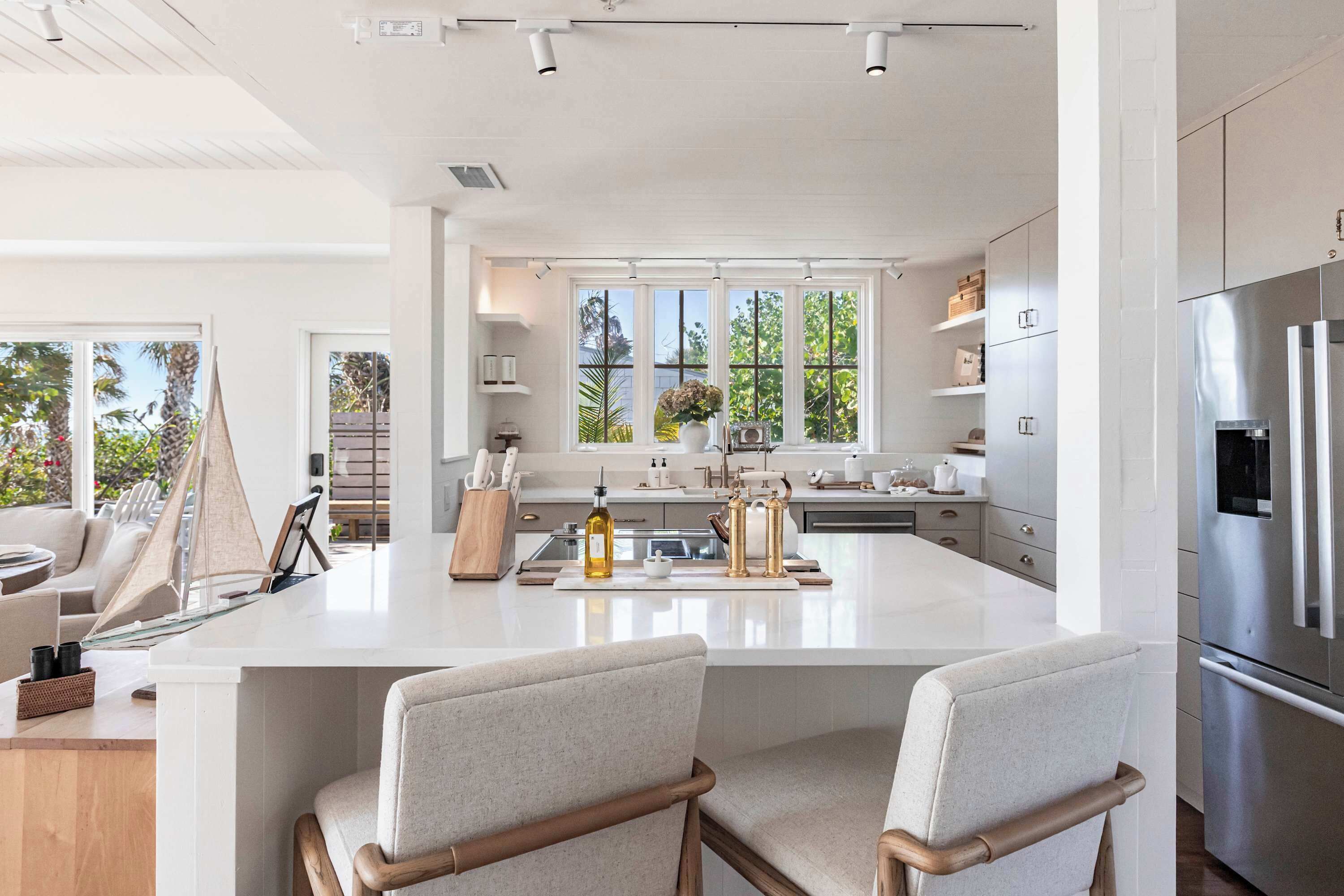 A modern kitchen with a large island, stainless steel appliances, and a view of the outdoors.