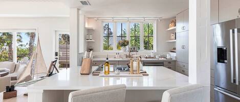 A modern kitchen with a large island, stainless steel appliances, and a view of the outdoors.