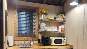 A compact kitchen with wooden cabinets, a built-in microwave, and a coffee maker. - Cherry Treesort “Traci’s Treasure” (Rowan County)