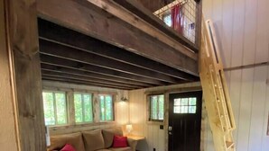 A spacious living room with a high ceiling, wooden beams, a sofa set, a coffee table, and a red rug. - Cherry Treesort “Traci’s Treasure” (Rowan County)