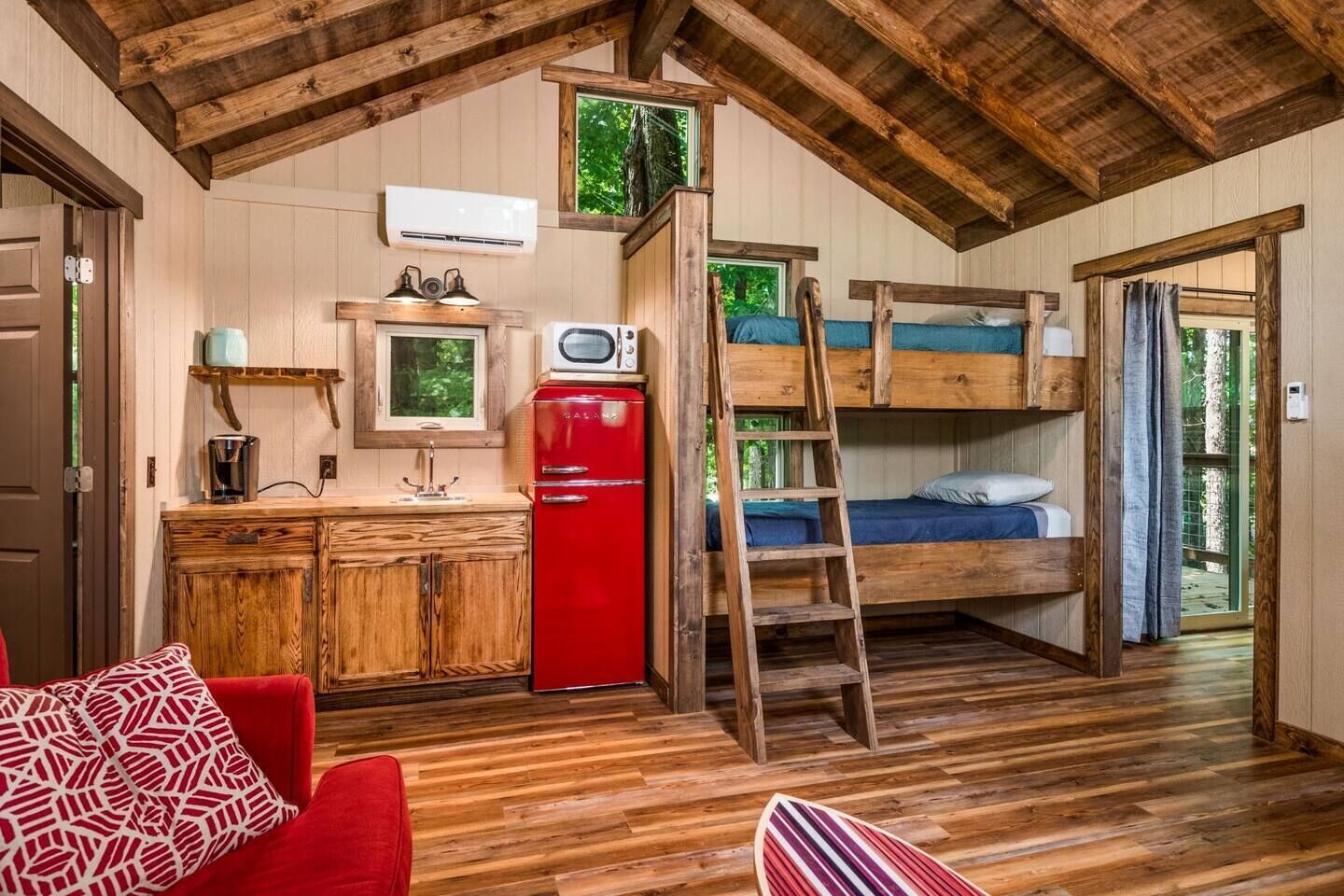 Une petite cabine comprenant un coin cuisine, des lits superposés et un plafond en bois.
